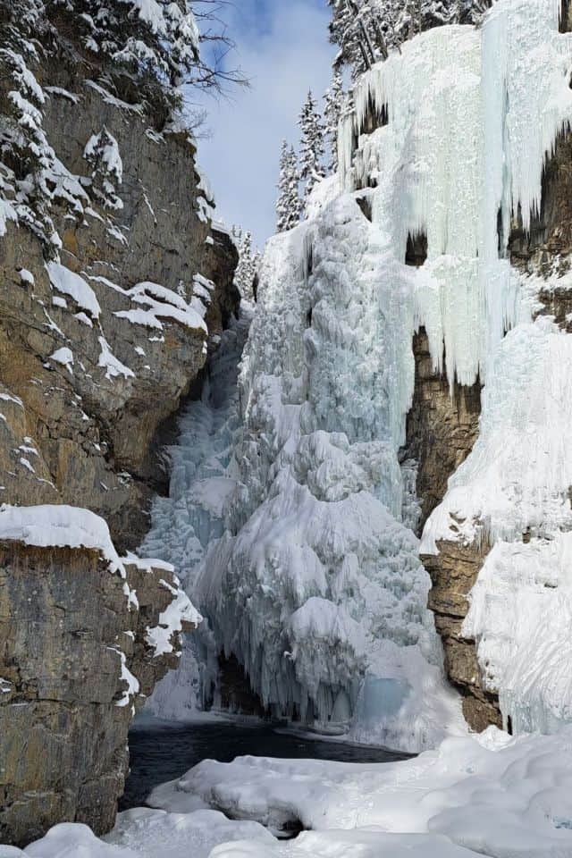 An impressive frozen waterfall and icicles cling to the cliff face in Johnston Canyon in Banff Alberta