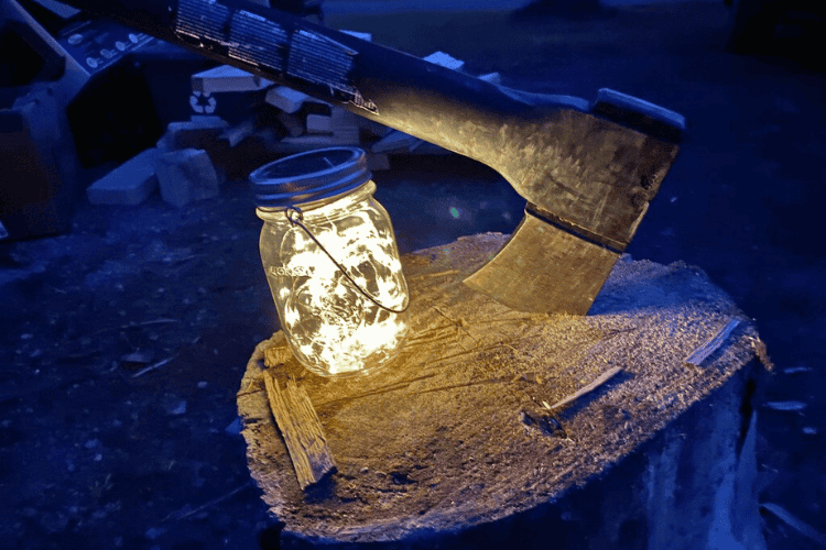 Solar powered mason jar twinkle lights from Glamping Essentials on a splitting log at the campsite.