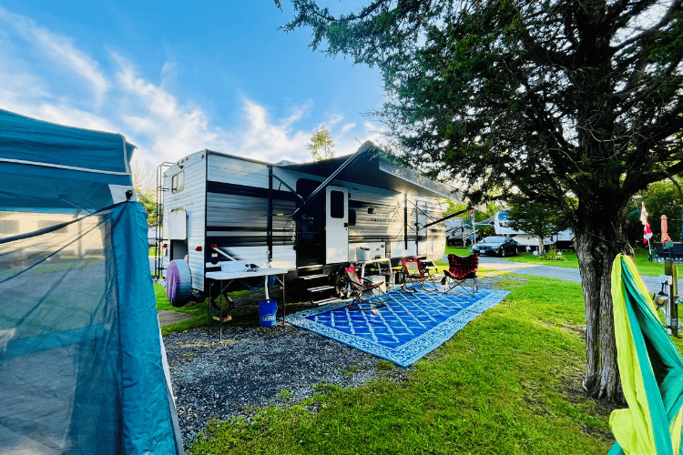 Campsite all set up for a weekend of camping, awning out, camping mat down, camp chairs set up.