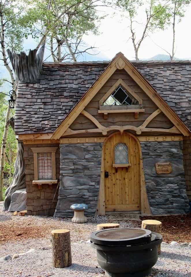Whimsical storybook cottage with cedar shake roof and rock-like entranceway.