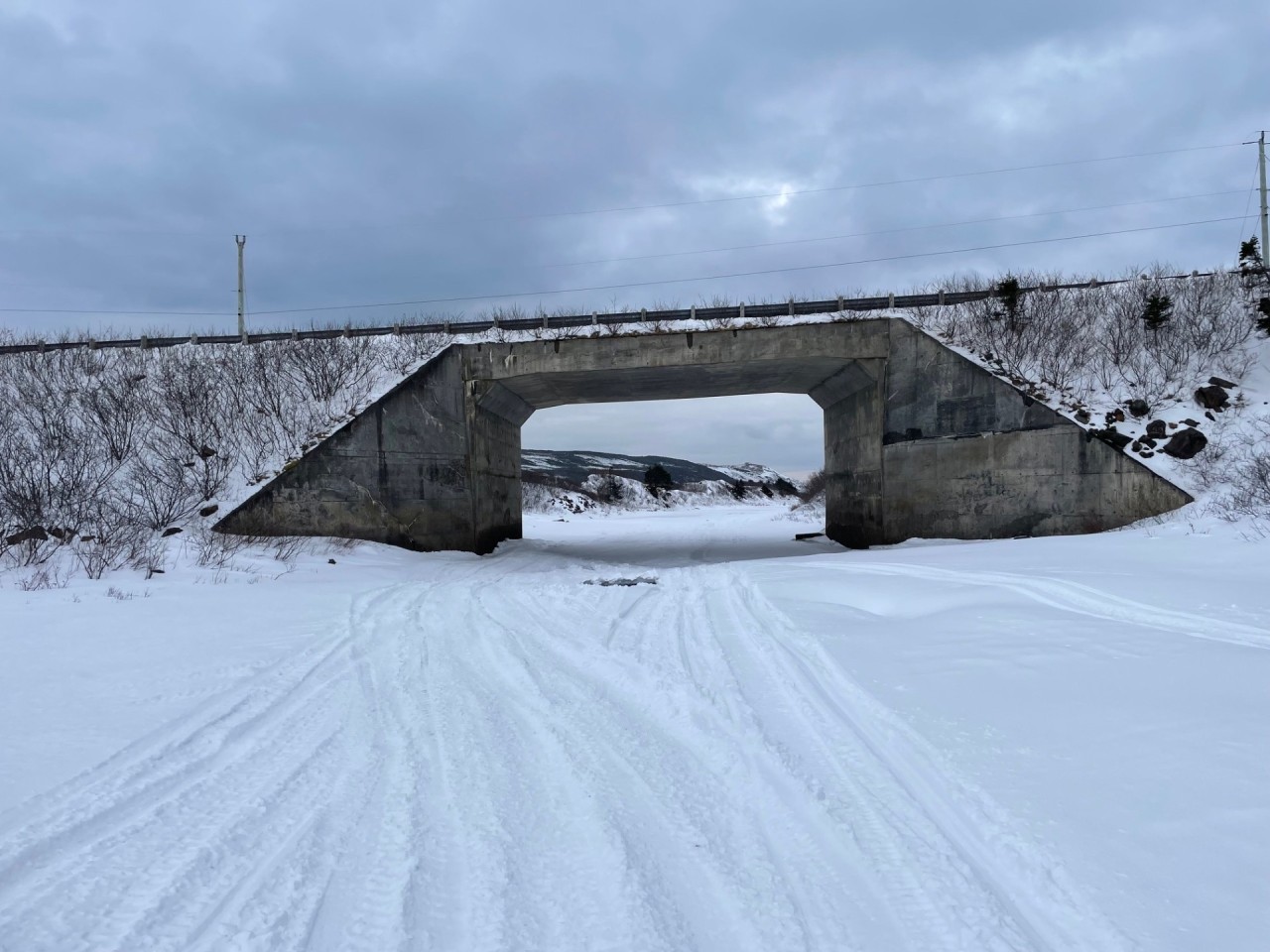 A Winter Walk on a Frozen River 2025-02-27 - Pretty much back to the road. Above the bridge is the road leading into the community. The river, of course, runs under the bridge. I'm not sure if you can see the ocean in the distance in this picture, but it's there! 